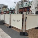 MurMur in Brighton with Lime Washed Wooden Rustic Cafe Barrier Posts and Cream Canvas Cafe Banners Finished off with Their Logo in Dark Grey, Cafe Banners, Bespoke Cafe Canvas Banners, Custom-Made Cafe Canvas Banners, Canvas Cafe Screens, Printed Canvas Cafe Banners, Printed Banners, Printed Cafe Banners, Bespoke Cafe Banners, Custom Banners, Pavement Banners, Pavement Barriers, Cafe Barriers, Cafe Barrier Posts, Fabric Banners, Commercial Cafe Barriers, Indoor Cafe Banners, Outdoor Cafe Banners, Heavy Duty Cafe Barriers, printed cafe barriers, Cafe Windbreak